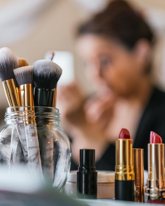 woman with make up brushes and cosmetics with lighted mirror